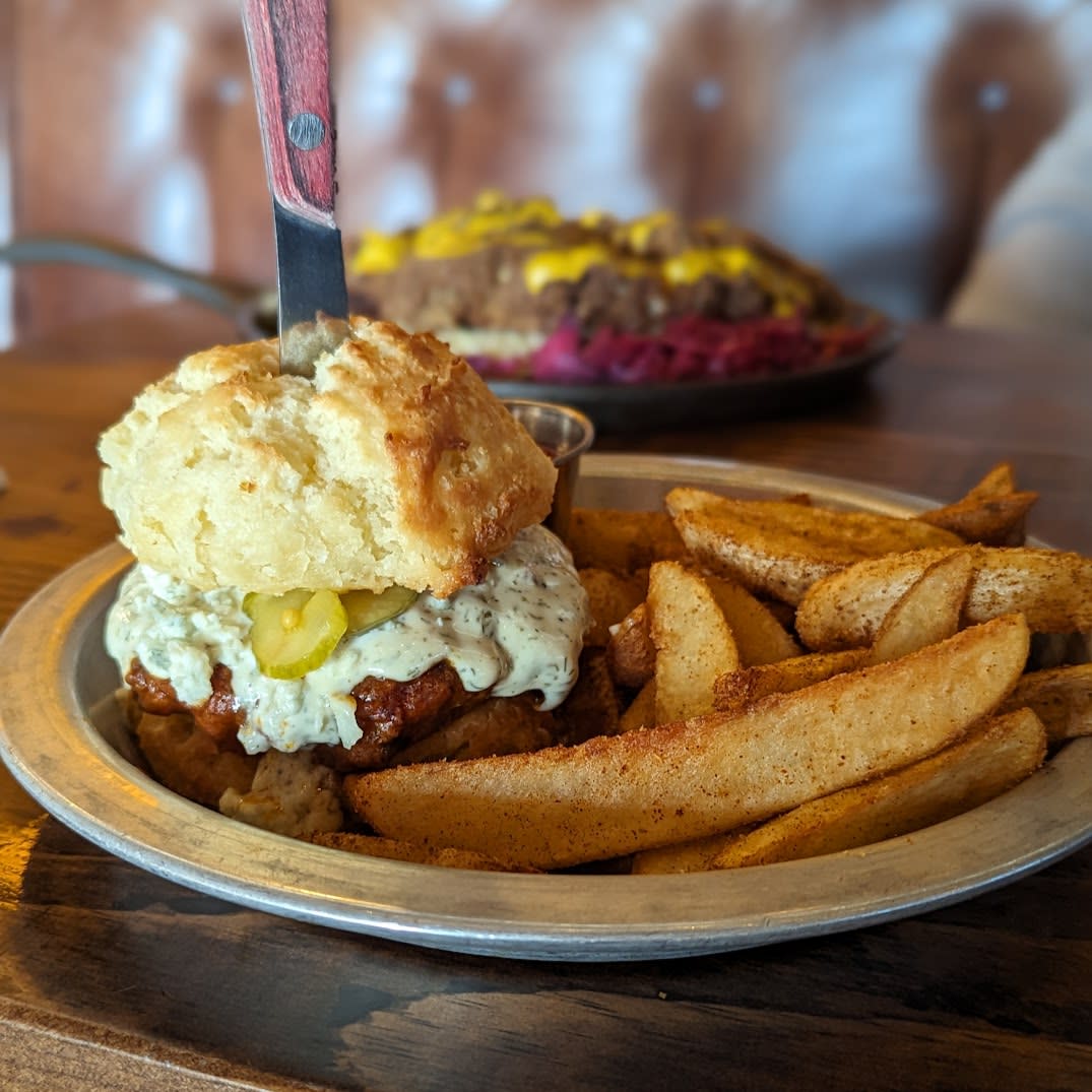Image is of the Buffalo Solider (buffalo chicken sandwich) on a biscuit with seasoned fries.