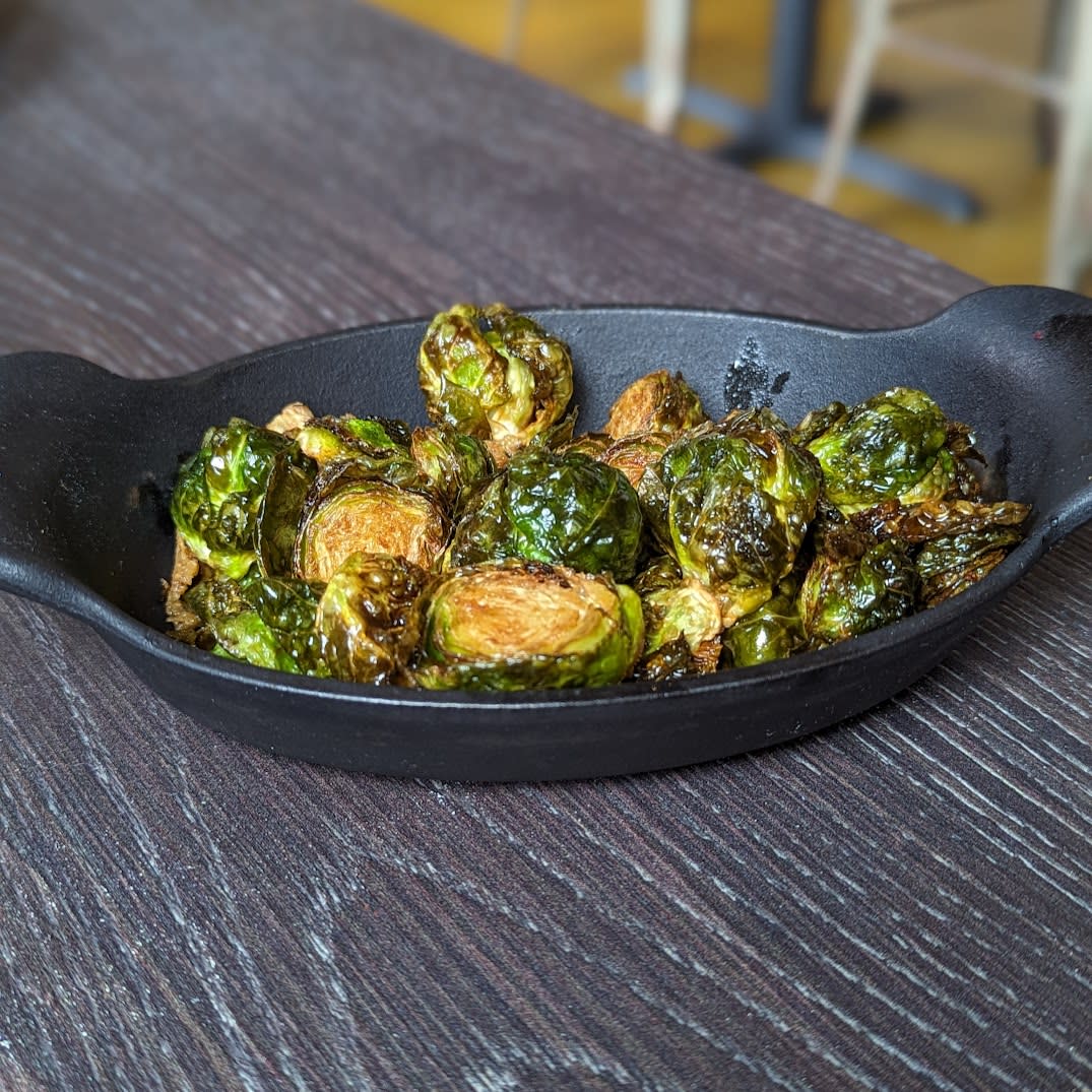 Image is of crispy brussels sprouts in a black cast iron bowl.
