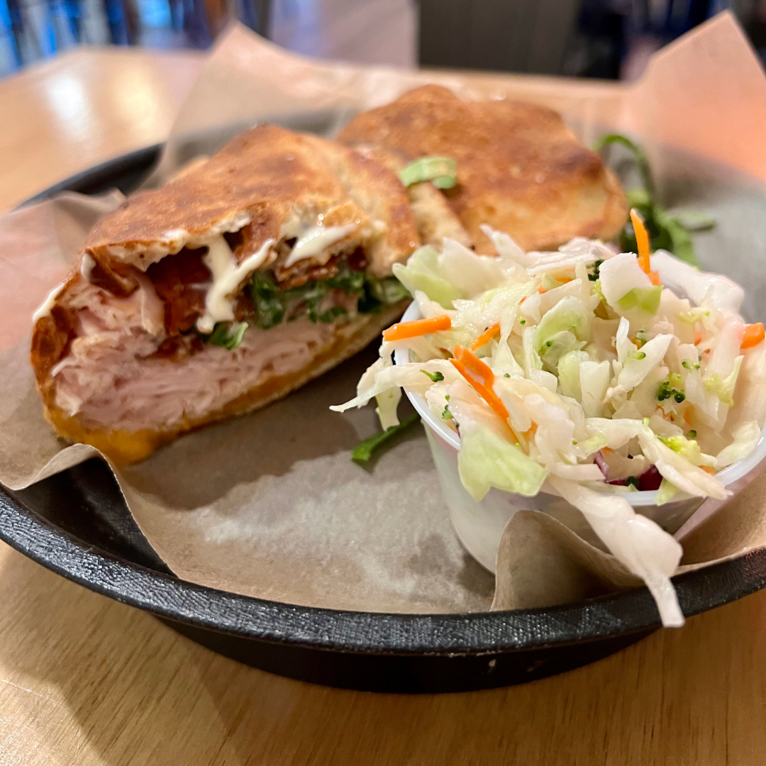 Close-up of MELD's Turkey Bacon Sandwich with fresh coleslaw on the side, showcasing a delicious meal option in Bentonville. Photo by Emily Neuman.