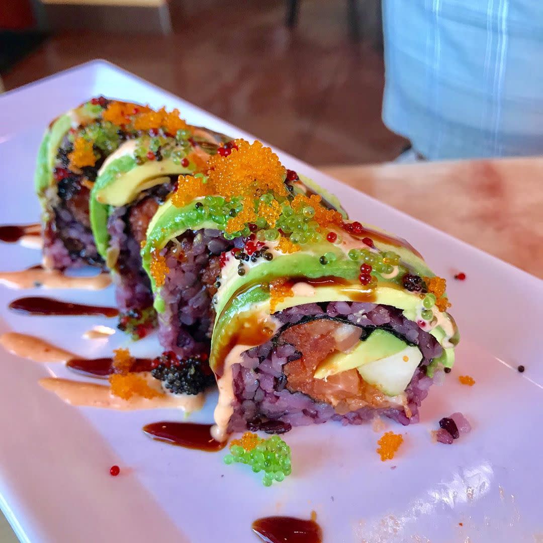 Purple colored sushi roll on white plate.