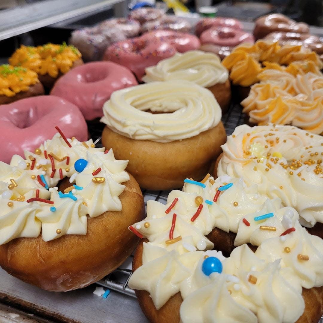 A close-up of colorful, freshly-made donuts with rich icing at Bluffs Bakery, one of the top spots to visit when exploring fun and tasty stuff to do in Cheyenne.