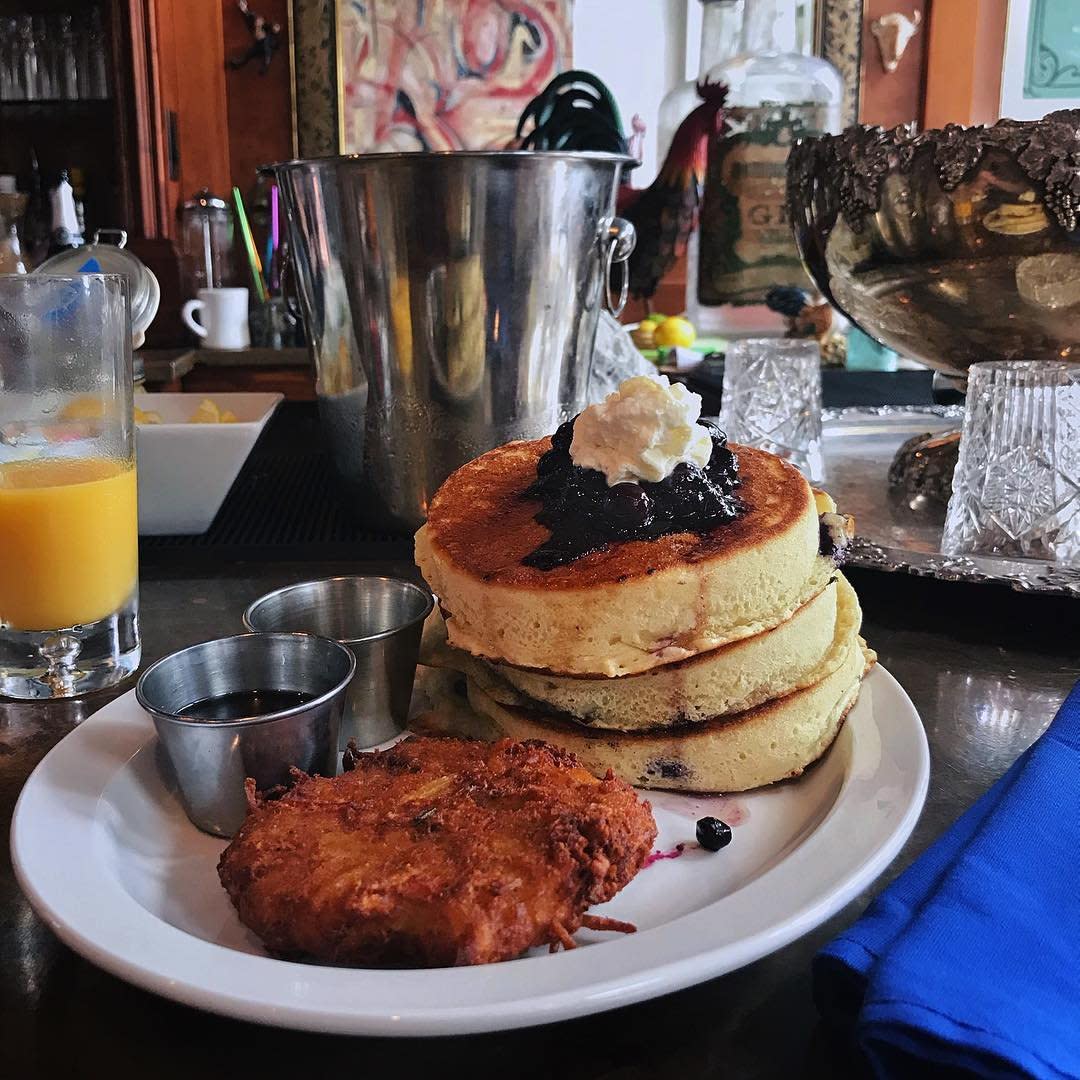 A plate of lemon blueberry pancakes with OJ and a potato cake at Otto's restaurant in Covington, Ky.