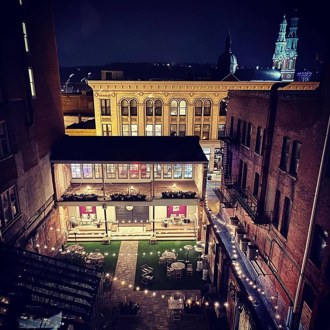 Looking down on an illuminated patio with brick walls and the turrets of Mother of God church in the background