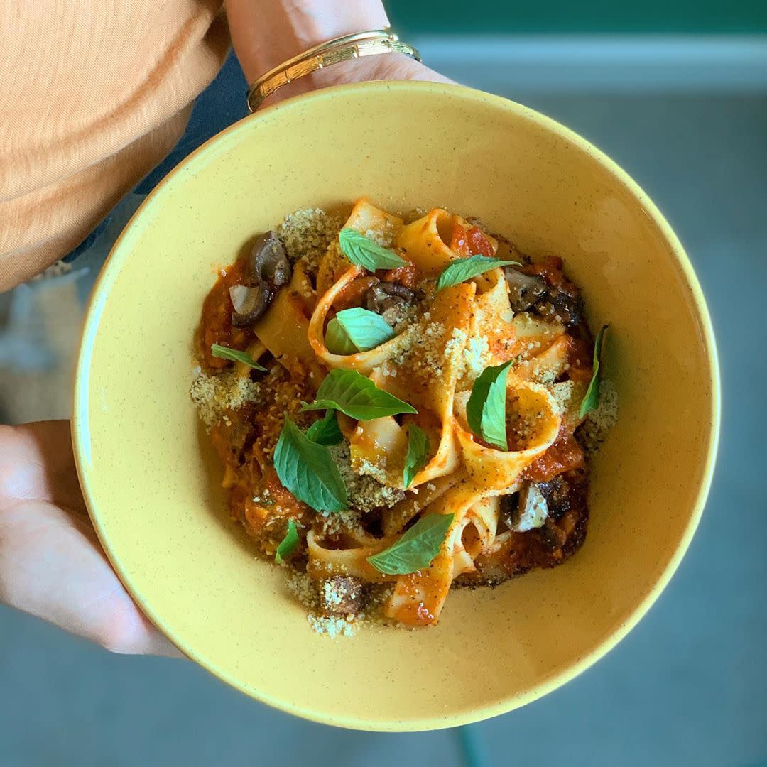 Yellow bowl filled with wide-noodle pasta in tomato sauce with mushrooms and vegetables from Frankie We Salute You!