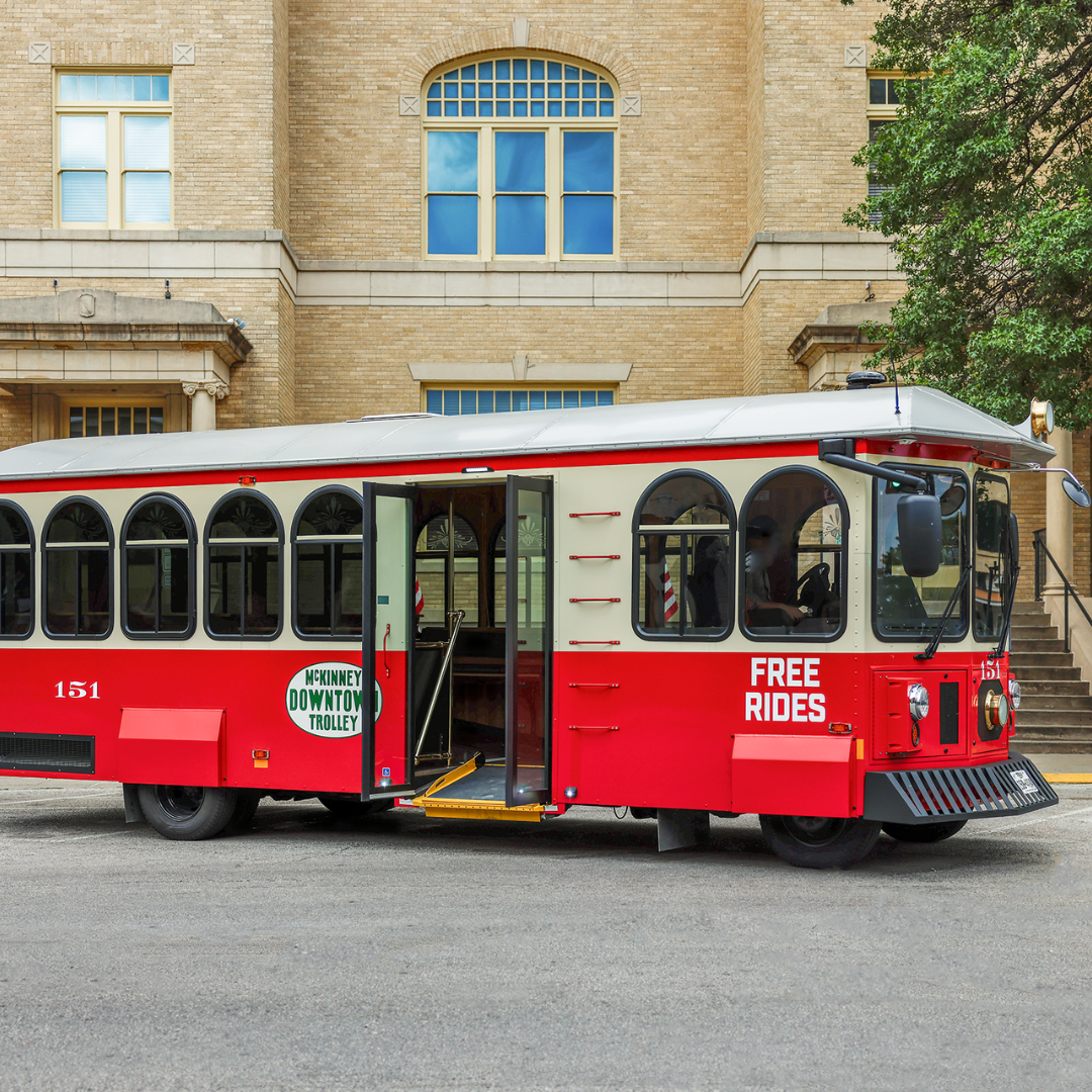 Red and white trolley car in front of a historic building