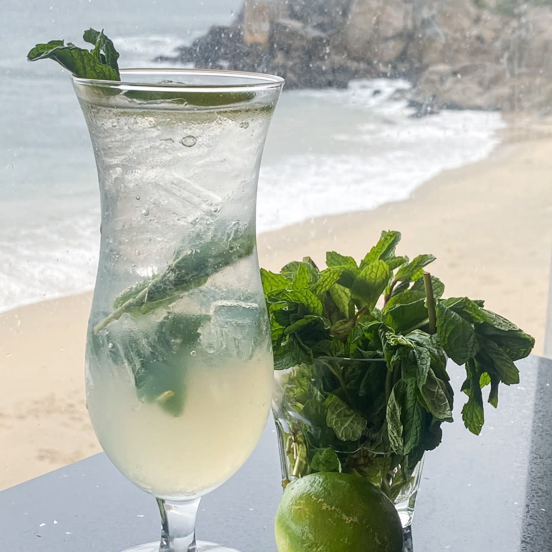 A cocktail sitting next to a window with a view of the beach