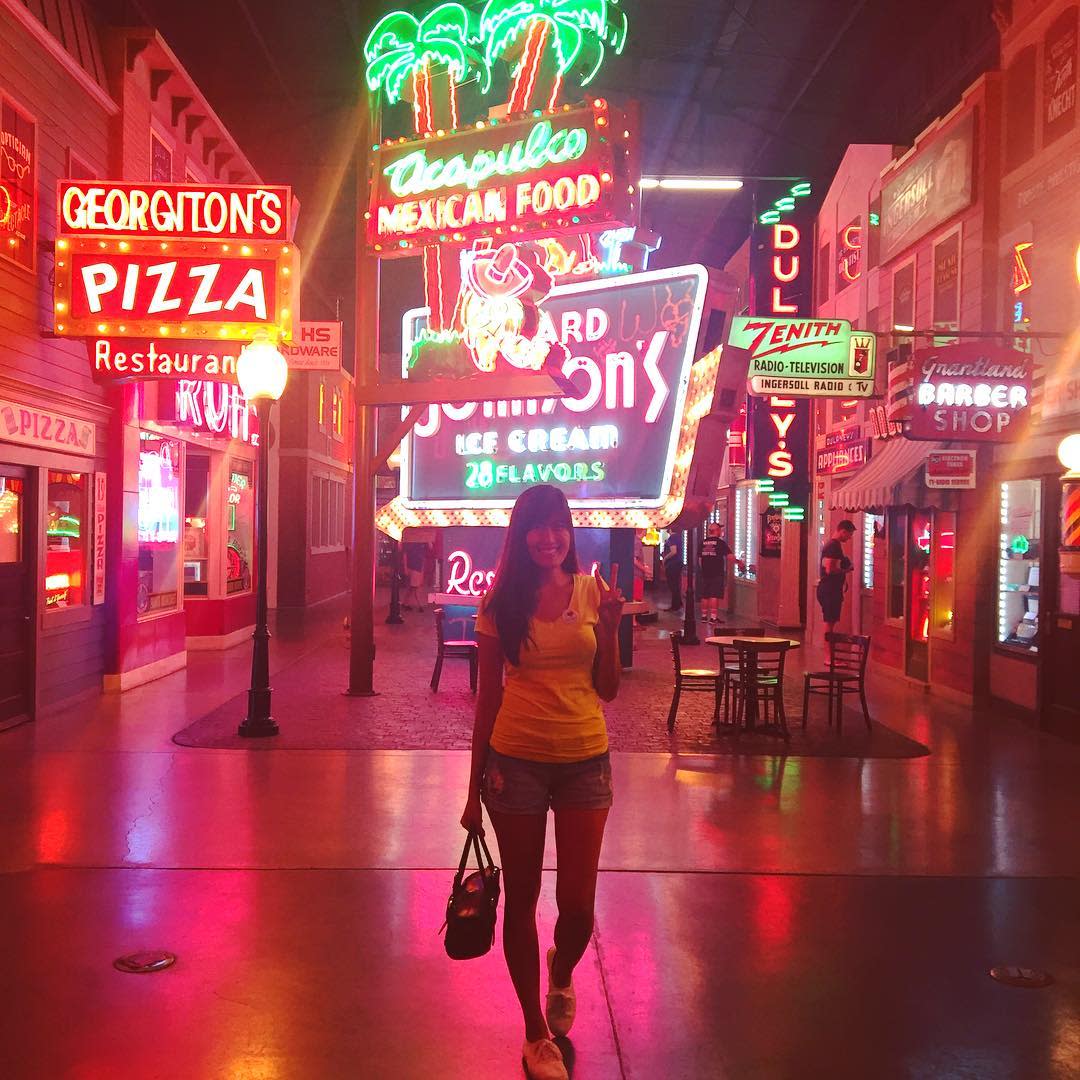 Inside the American Sign museum, a woman standing surrounded by neon signs