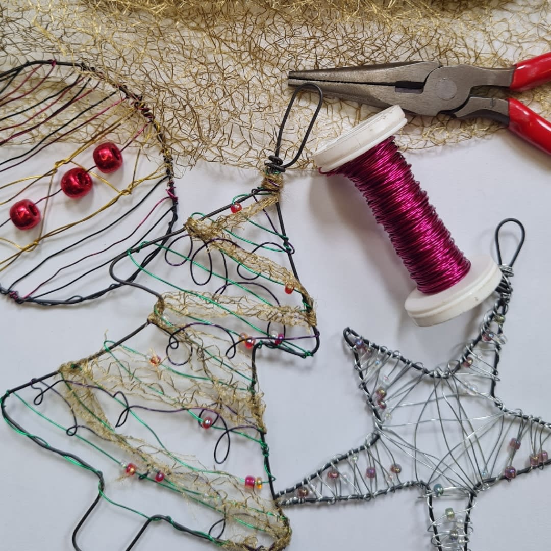 Assortment of Christmas wire ornaments next to a set of pliers and wire, including a bauble, tree and star