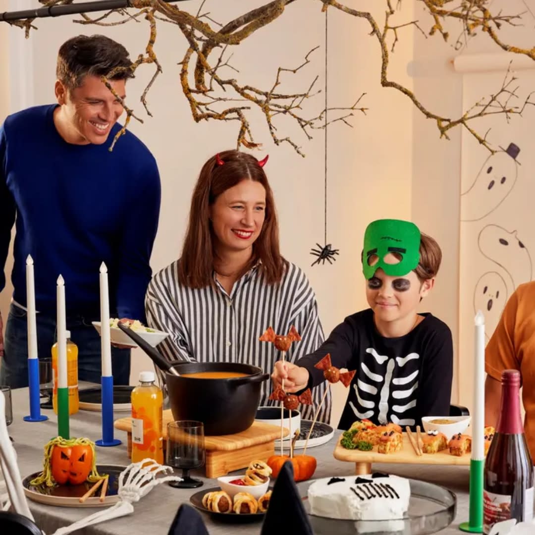 Boy with a skeleton costume and mask enjoying halloween treats with parents