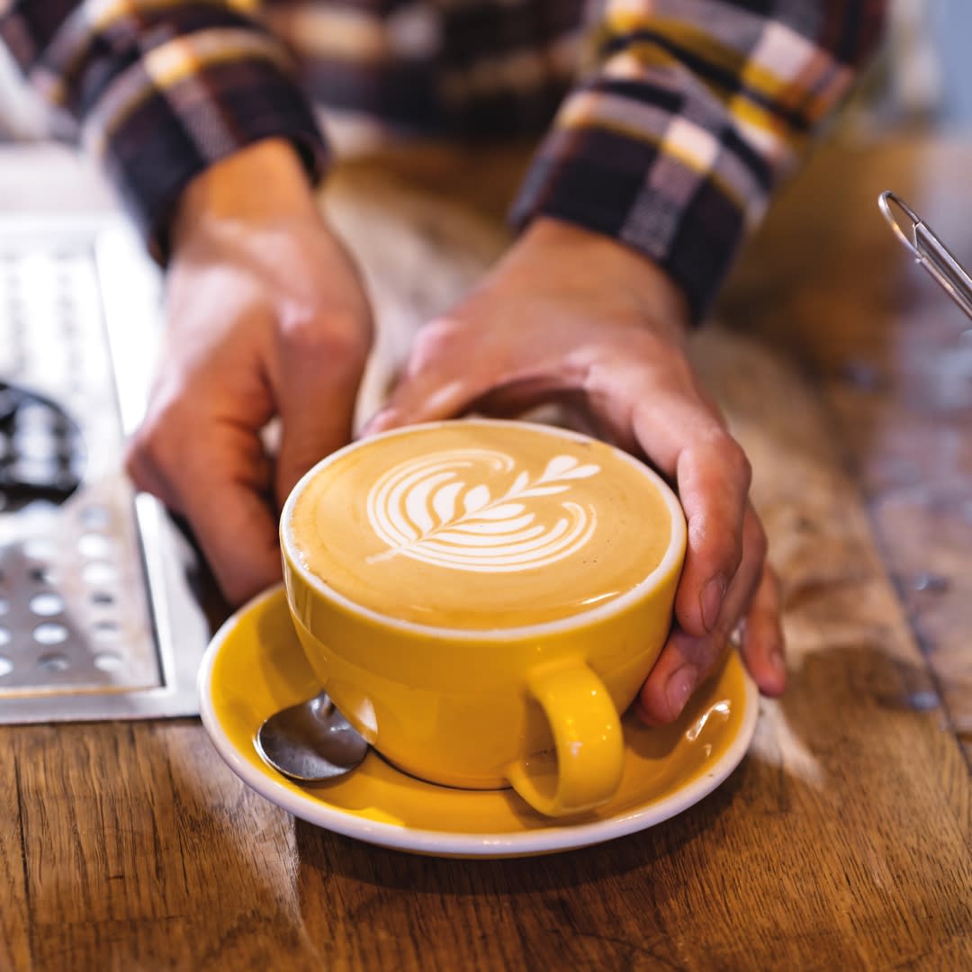 Yellow mug of coffee with latte art at Mettricks