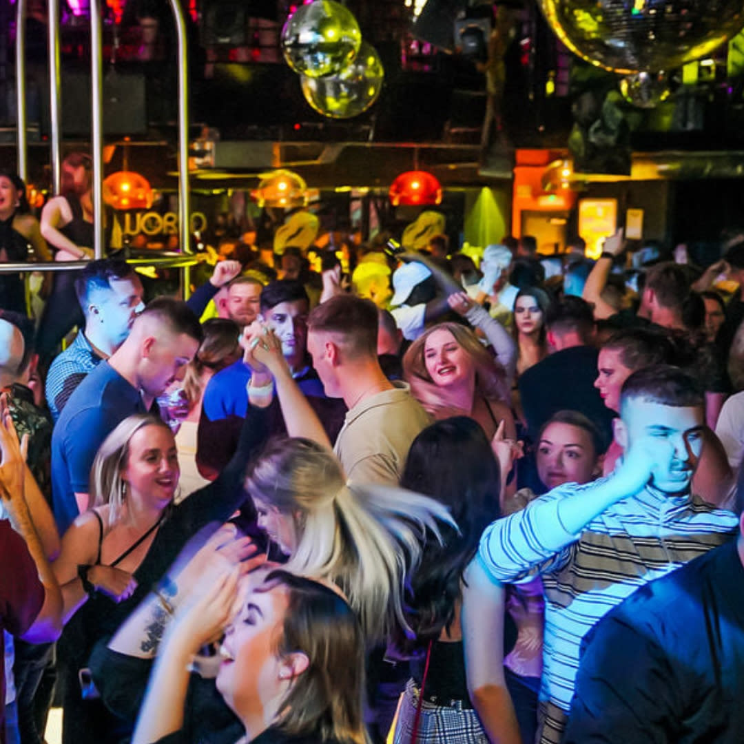 Club goers dancing under a disco ball on the dancefloor at Popworld