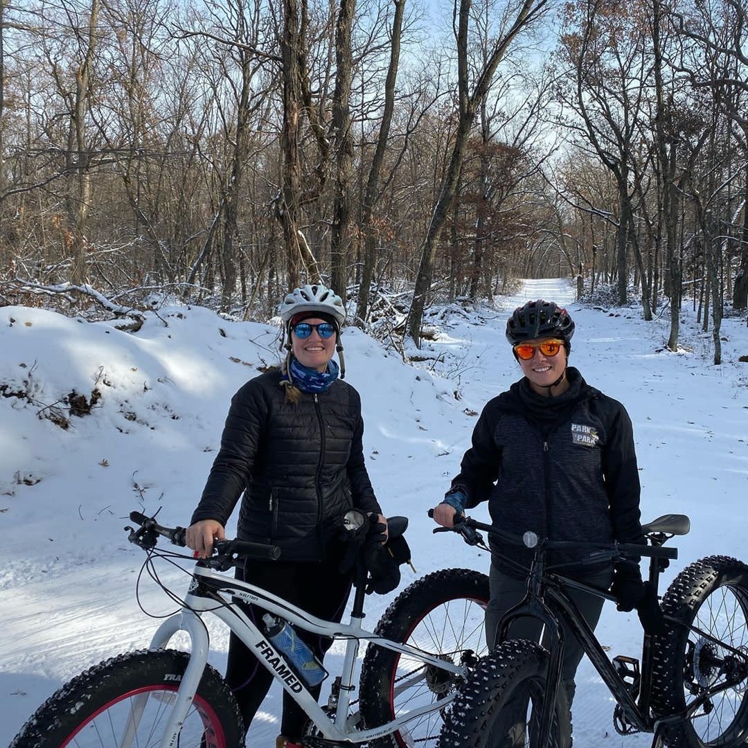 Two people standing in snowy trail with fat tire bikes