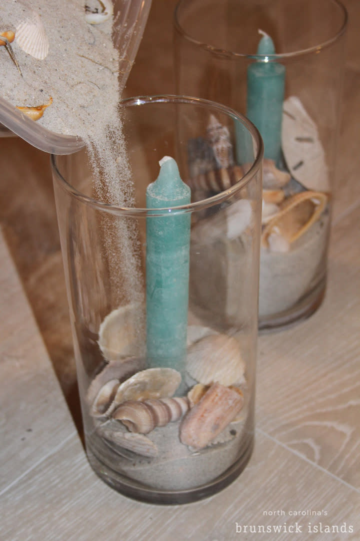 Pouring sand into a candle with seashells
