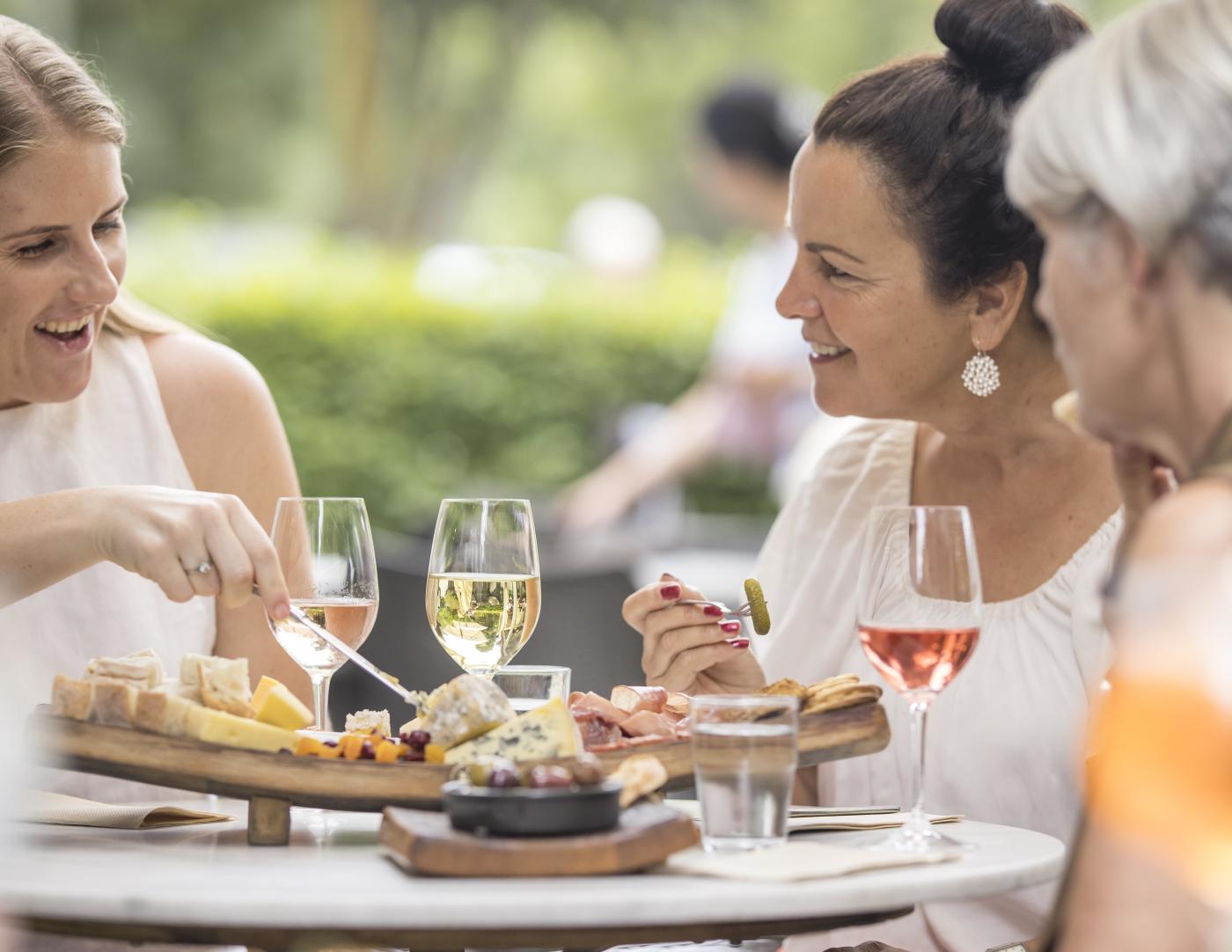 People enjoying wine and cheese platter.