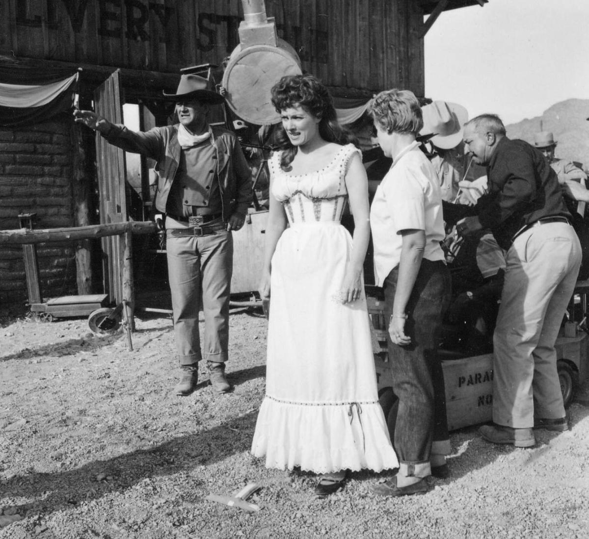 old black and white photo with a women in a white dress and several men in a western setting