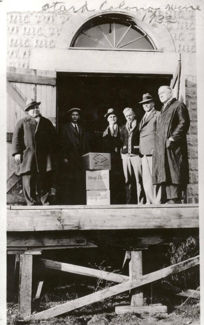 Six men stand on the loading docks of Calona Wines