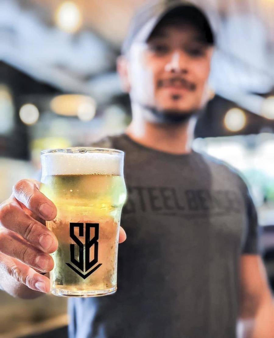 A Steel Bender Brewyard employee holds a glass of beer