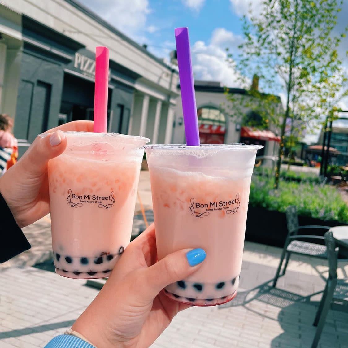 Two pink boba tea drinks from Bon Mi Street with Newport on the Levee in the background