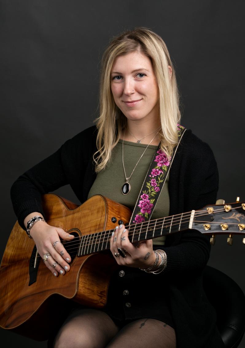 Local musician Xarika playing guitar with dark background