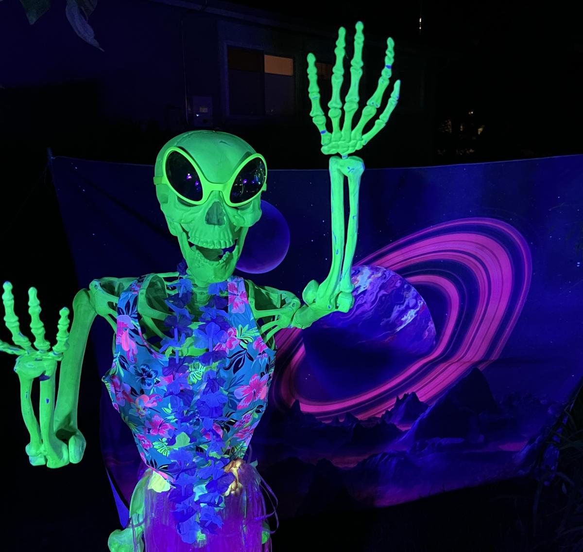A neon green glow in the dark skeleton dressed in Luau garb