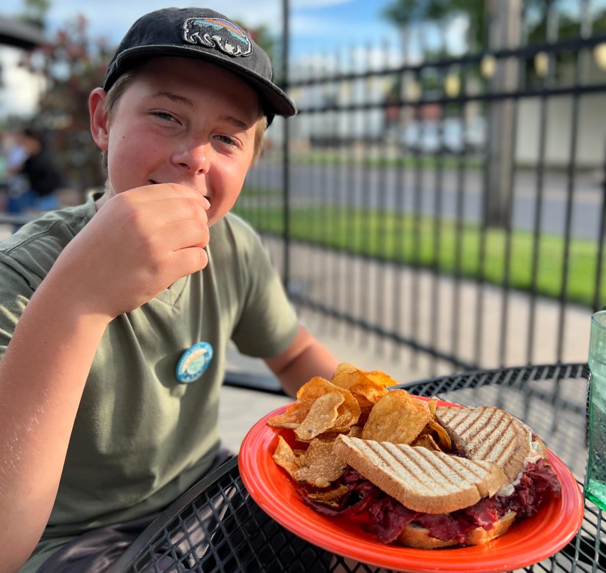 A boy eats his sandwich on the patio of Monarch