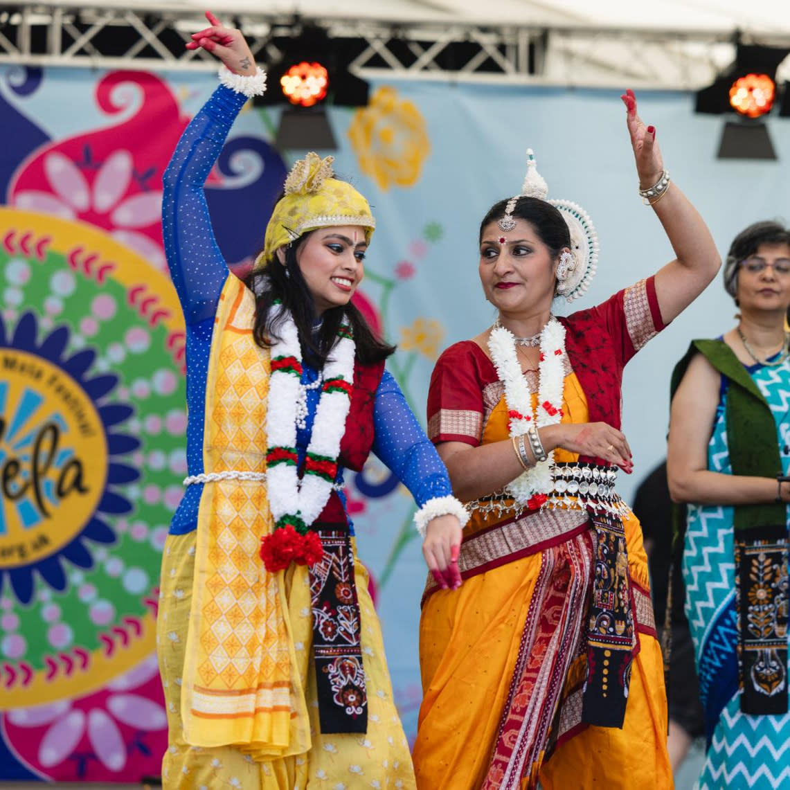 Two women dressed in traditional Indian attire dance on Mela Festival stage