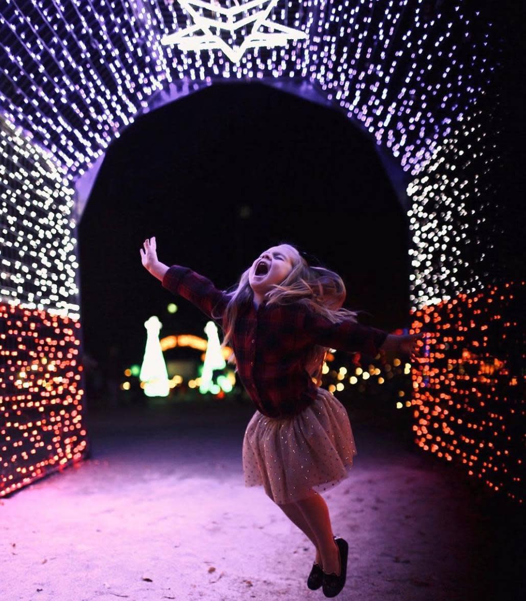 girl jumping under Christmas lights