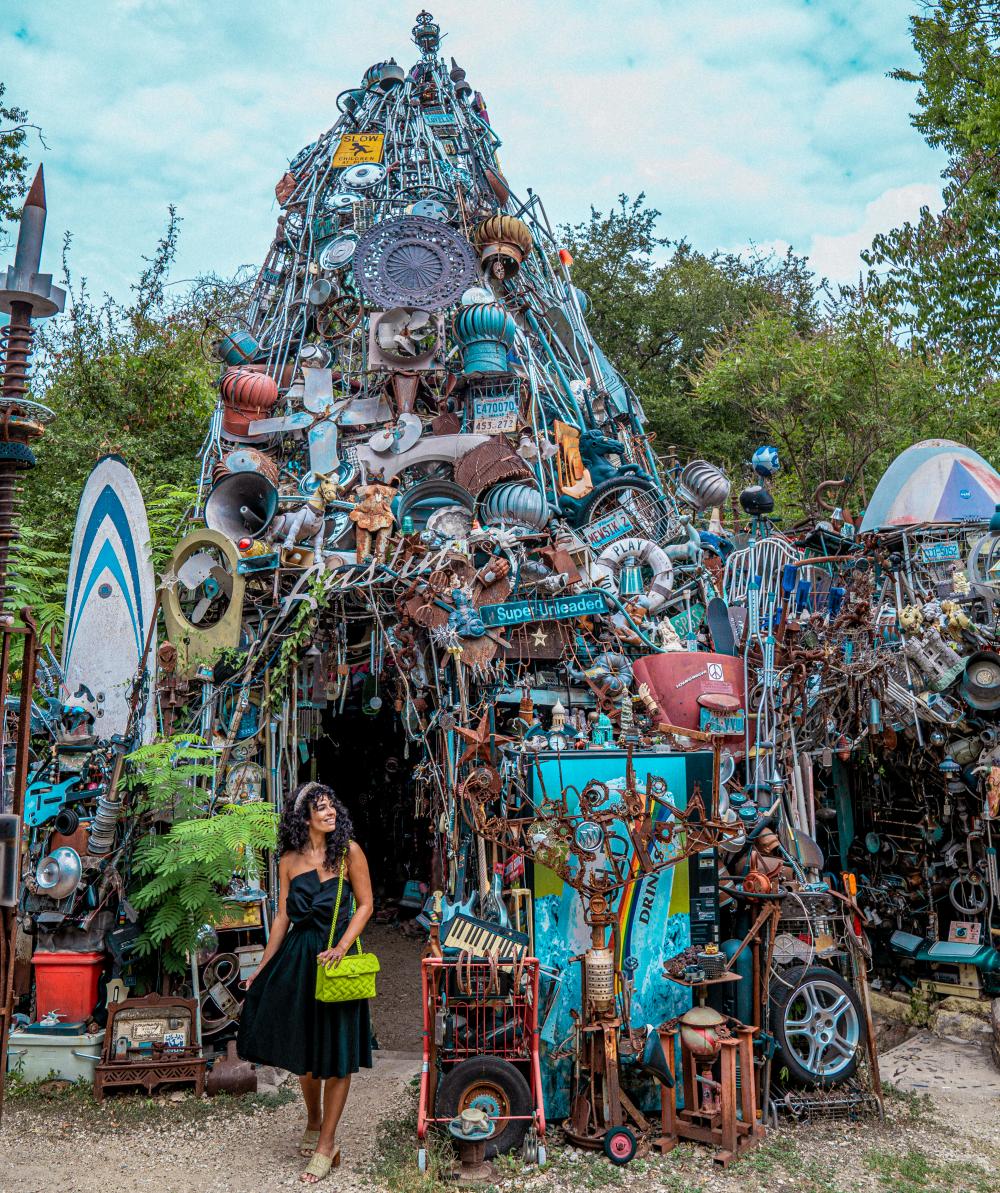 Woman standing in front of giant pile of recycled material in the shape of a fort.