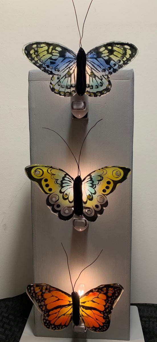 Three nightlight lamps made of glass and shaped into different colored butterflies