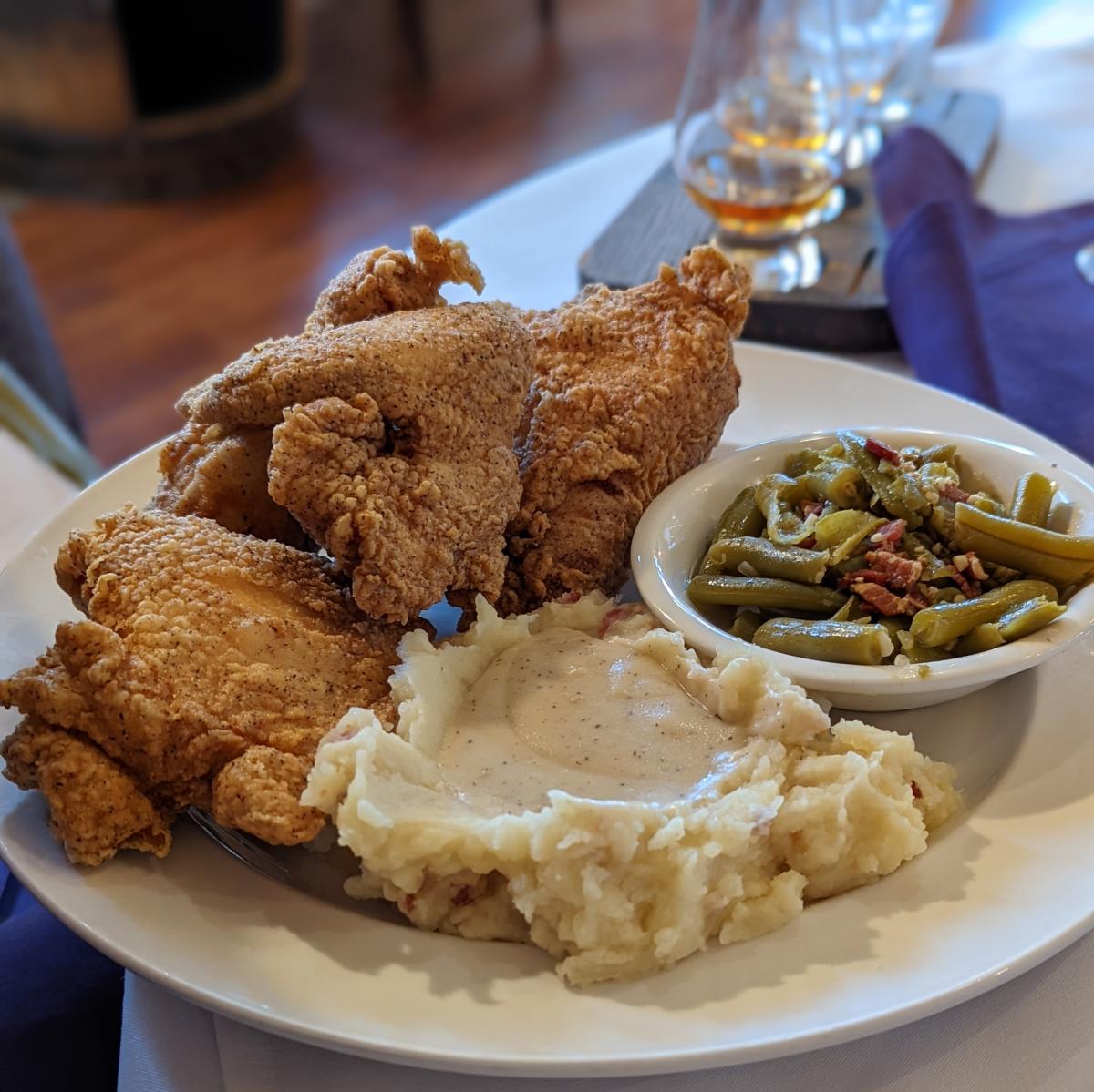A white plate with fried chicken, green beans and mashed potatoes at Purple Poulet