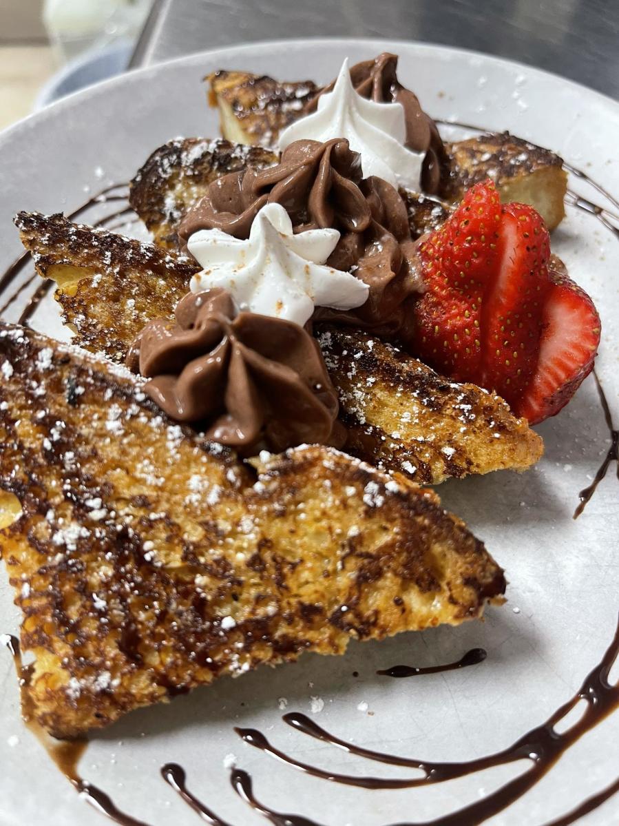 a plate of french toast decorated with chocolate whipped cream and strawberries from New Day Cafe in Leland
