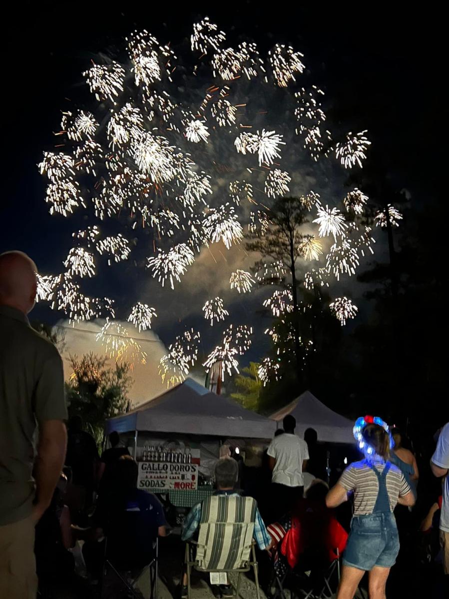 Fireworks exploding over Abita Springs as guests watch.