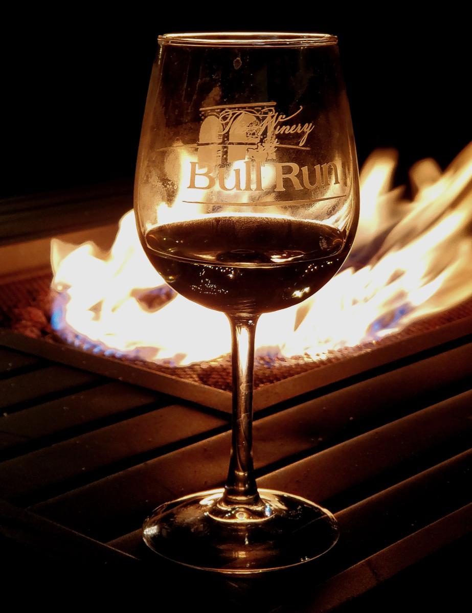 Glass of red wine positioned in front of flaming fire pit