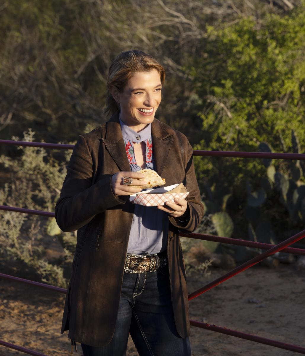 Jen Chase holding a taco with a lush desert background