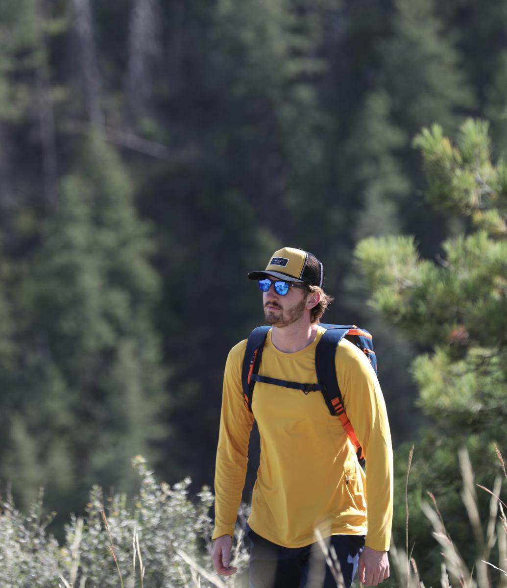 Person hiking with a Tellus yellow long sleeve shirt and backpack