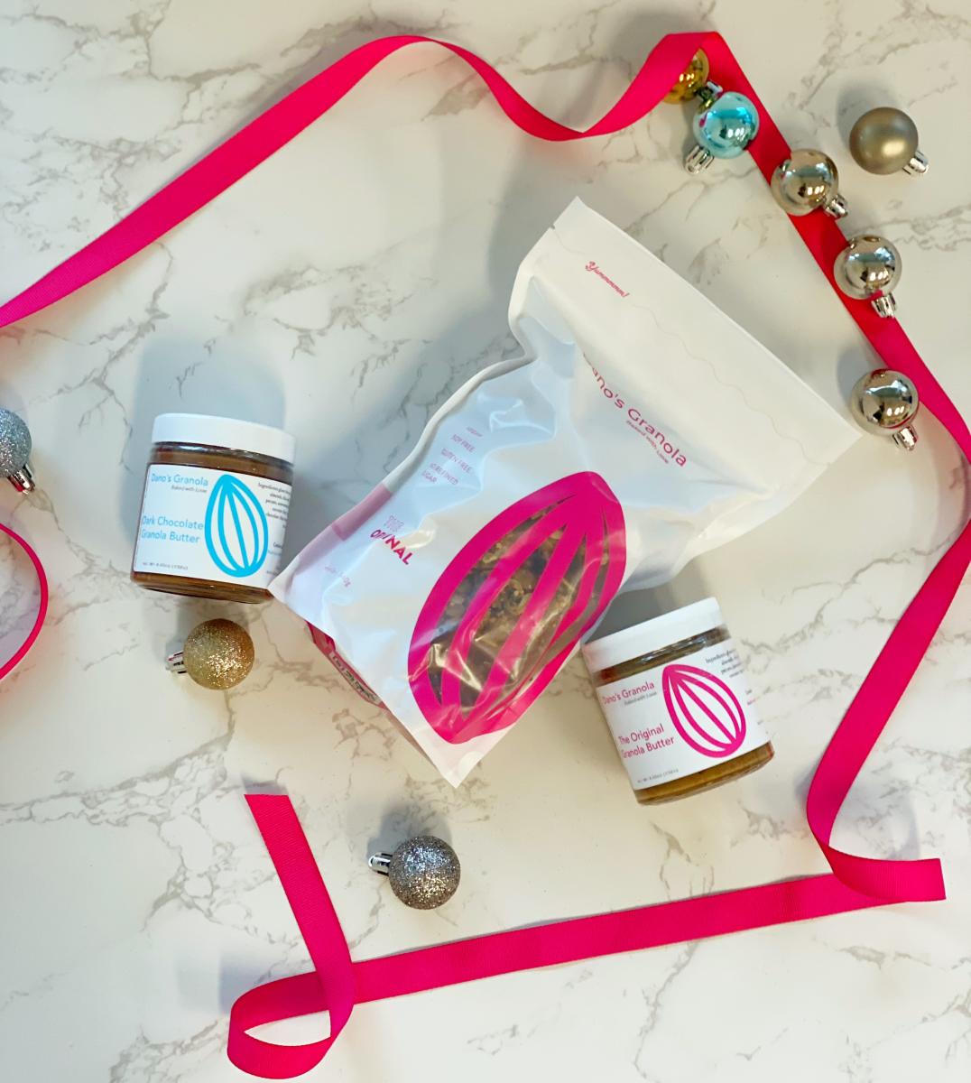 Bag of granola surrounded by Granola butter jars and holiday ornaments and ribbons