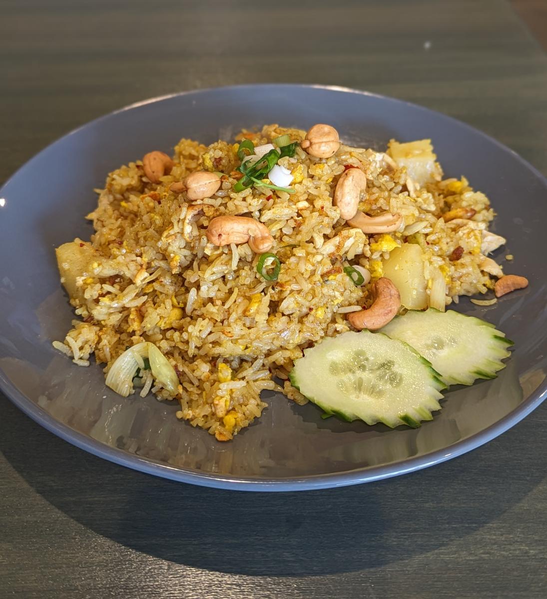 Image is of rice, cashews, chicken and pineapple on a plate.