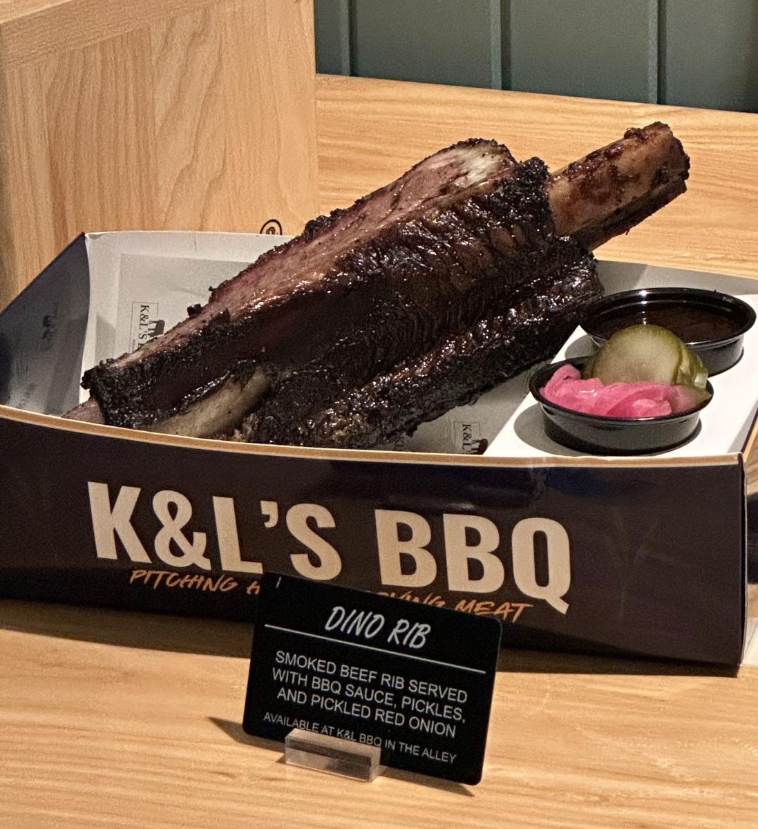 K&L’s BBQ smoked Dino Rib served with barbecue sauce, pickles and pickled red onion.