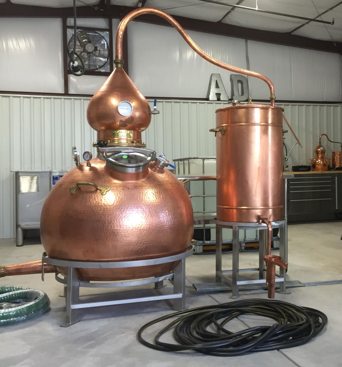 A copper still sits inside a warehouse