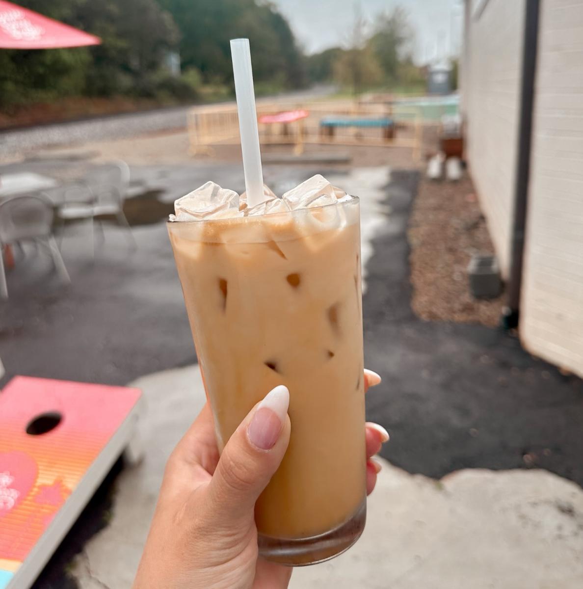 Someone holds an iced coffee in front of the camera.