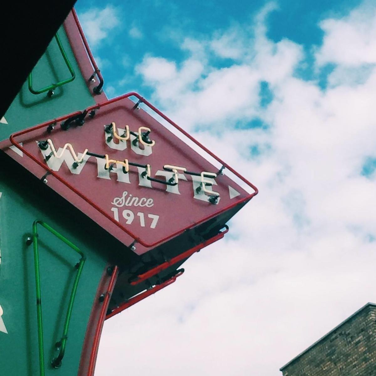 ug white sign with clouds in the background