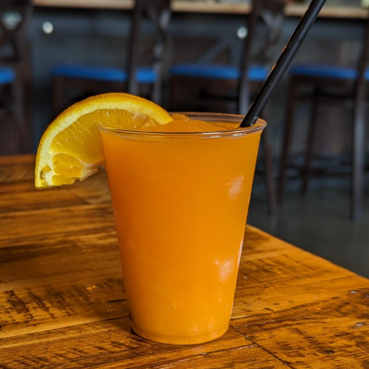 Image is of the Orange Creamsicle Frozen Cocktail with a straw and orange on the side.