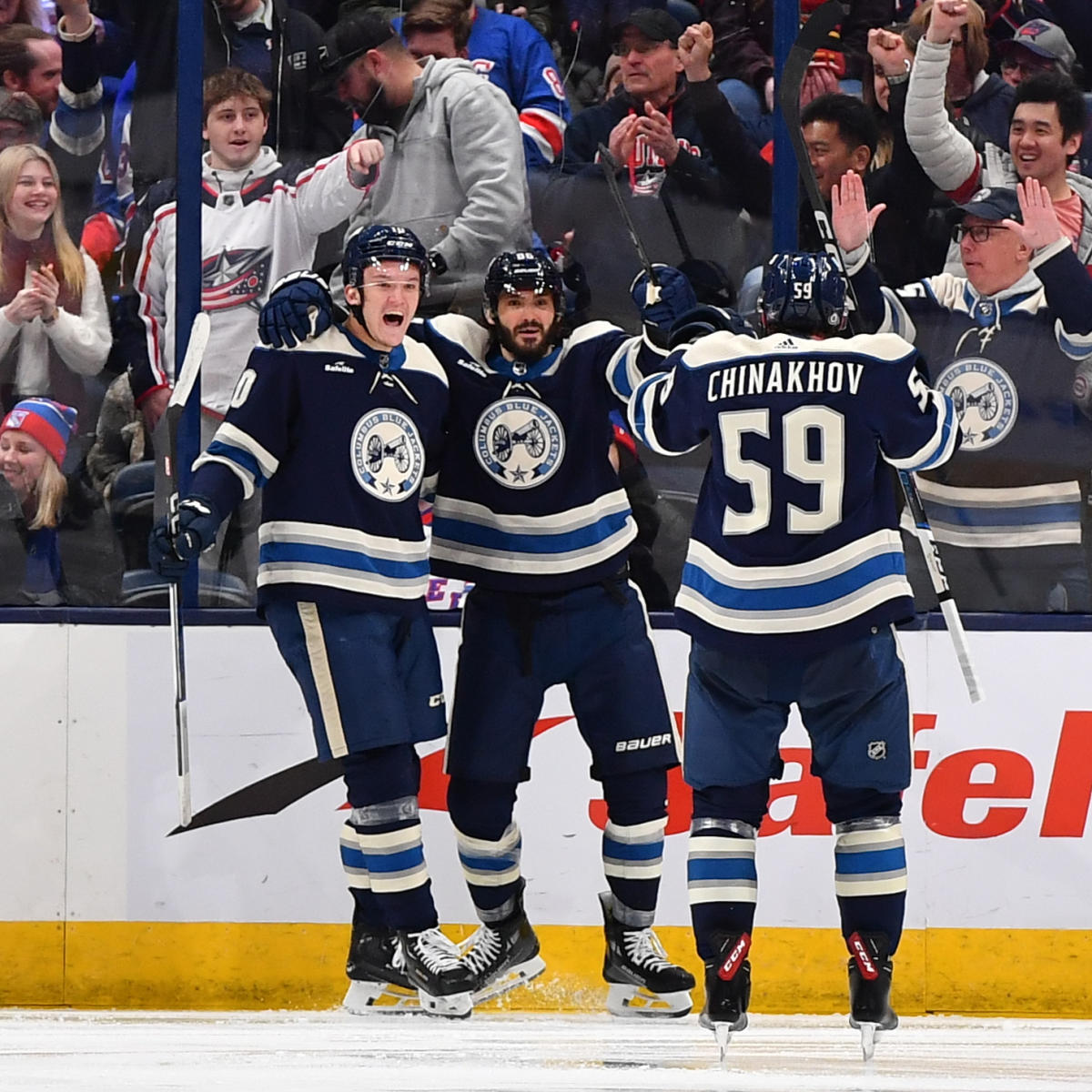 Three Columbus Blue Jackets players celebrating a goal on ice