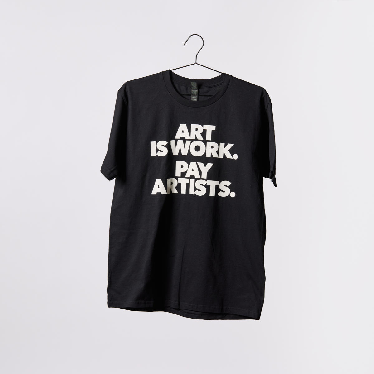 Black t-shirt with white bold letters that say "ART IS WORK. PAY ARTISTS."