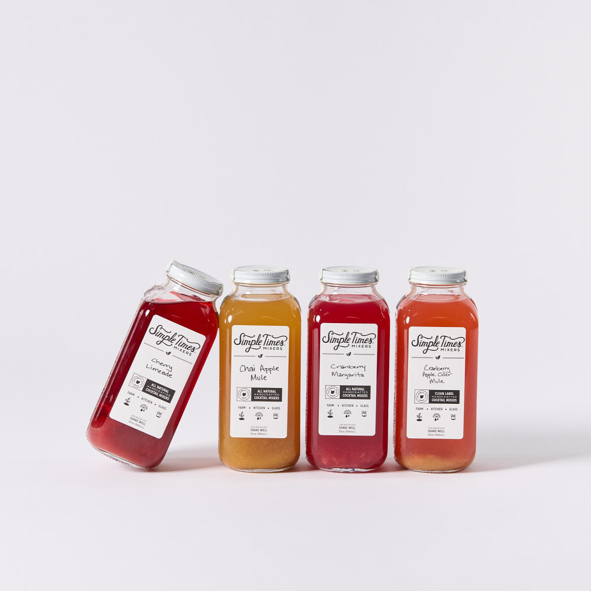 Four 32oz bottles of fruit-flavored cocktail mixers from Simple Times Mixers standing next to each other
