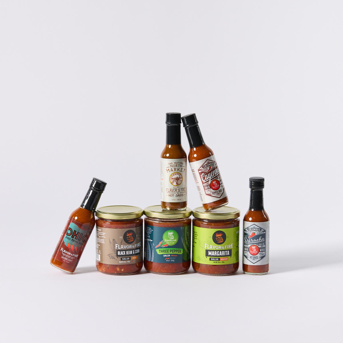 Assortment of hot sauces and salsas from Flavor & Fire stacked on top of each other
