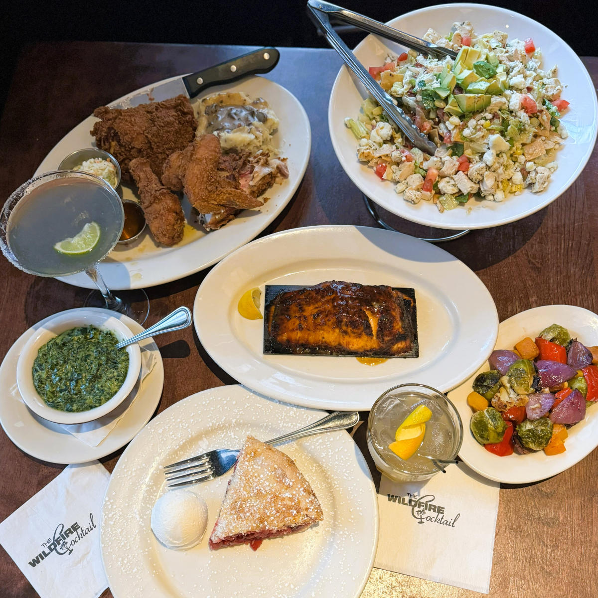 Table of food: Fried chicken, chopped salad, glazed salmon, and cherry pie.