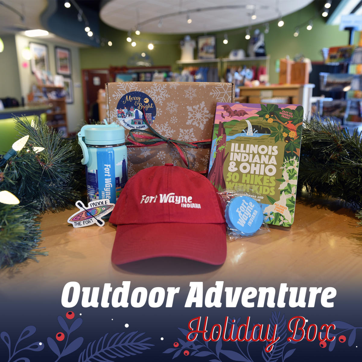 Gift box showing kids items including a stainless steel Fort Wayne skyline thermos, kayak sticker, Fort Wayne hat, Fort Wayne can topper, and 50 Hikes with Kids book