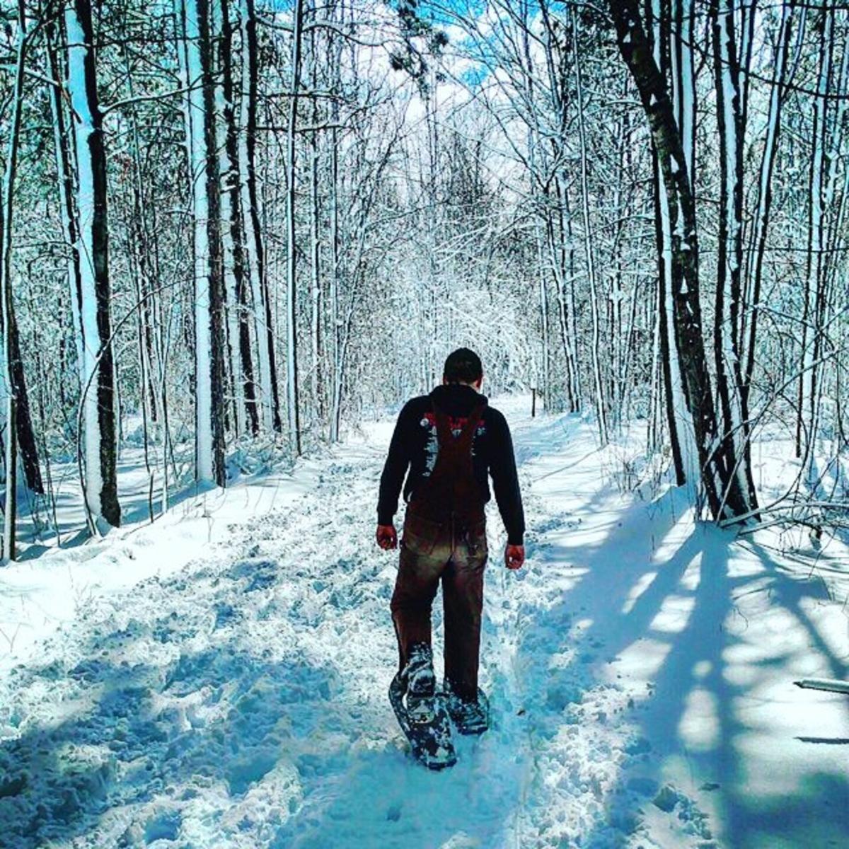 Man snowshoeing on winter-white trails at Midland City Forest