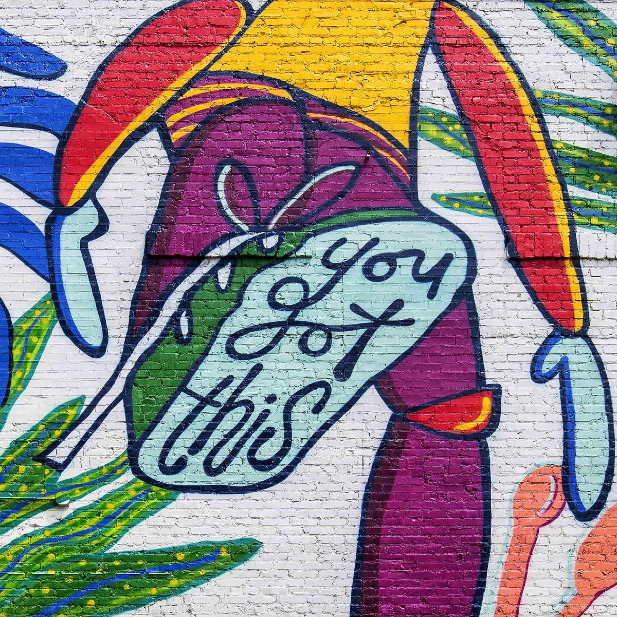A mural on the side of Run-In in Greenville, SC with a person lifting their foot, which says "You Got This" on the bottom of the shoe.